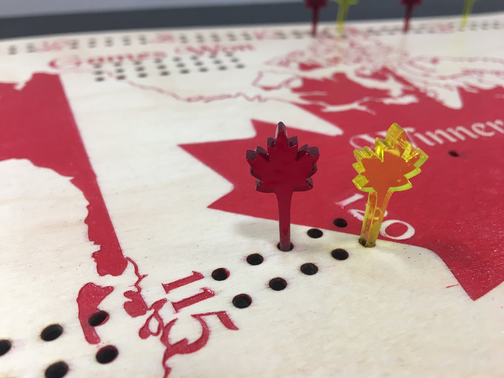 Close-up of a cribbage board with pegs, including a red and a yellow peg.