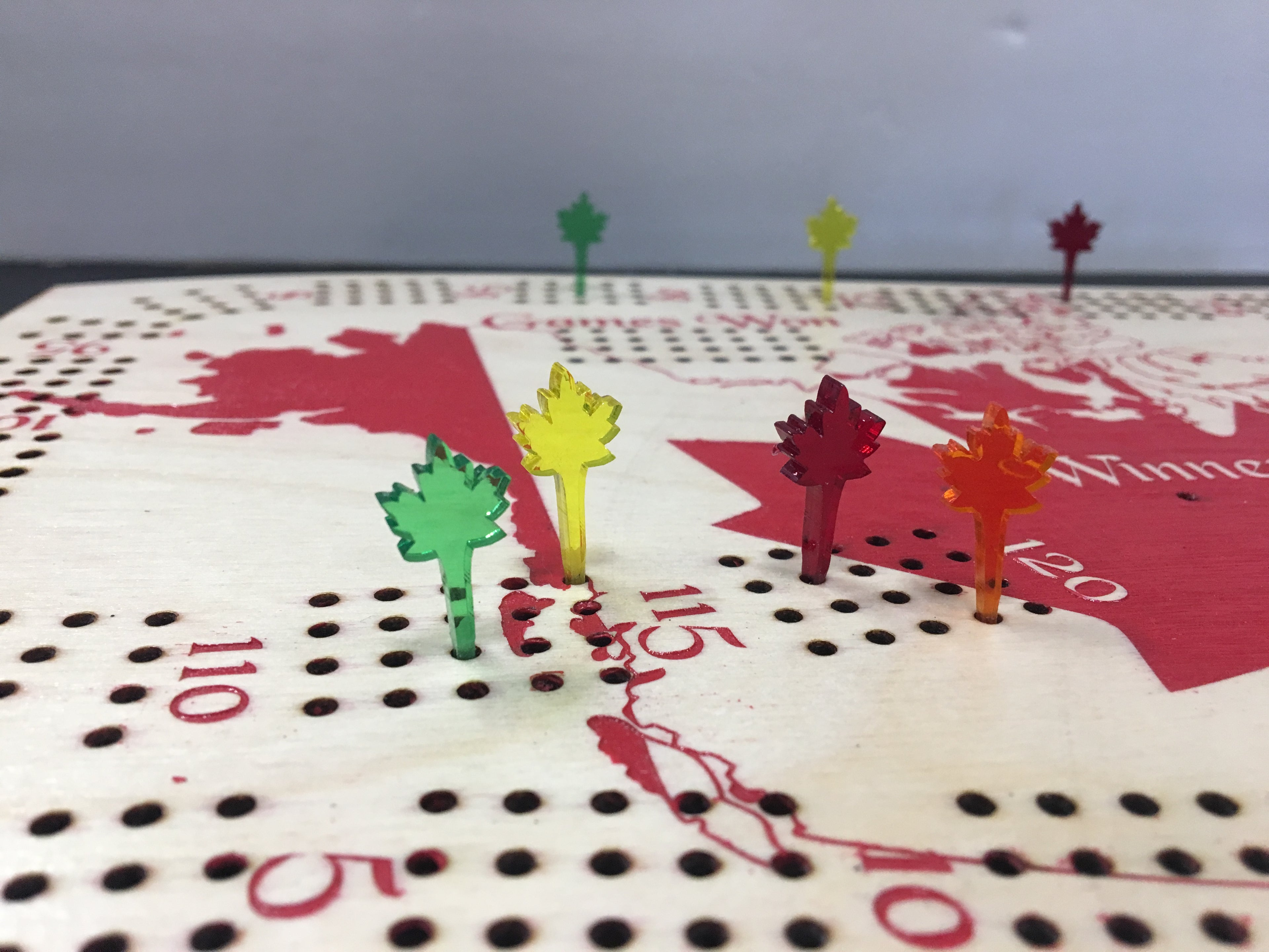 Colorful leaf-shaped pins on a cribbage board with a white background