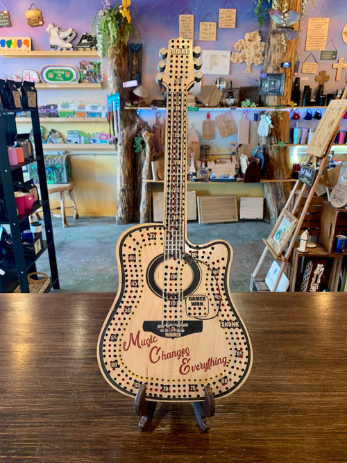 Wooden guitar-shaped cribbage board with 'Music Changes Everything' text.