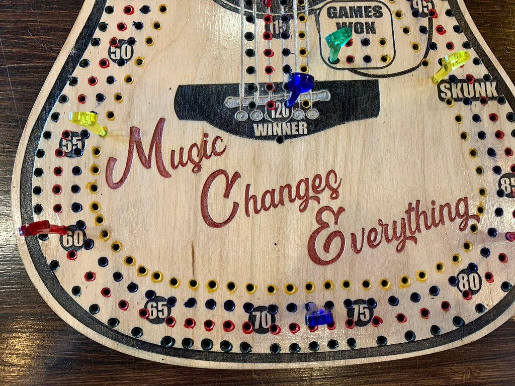 Wooden guitar-shaped cribbage board with 'Music Changes Everything' text.