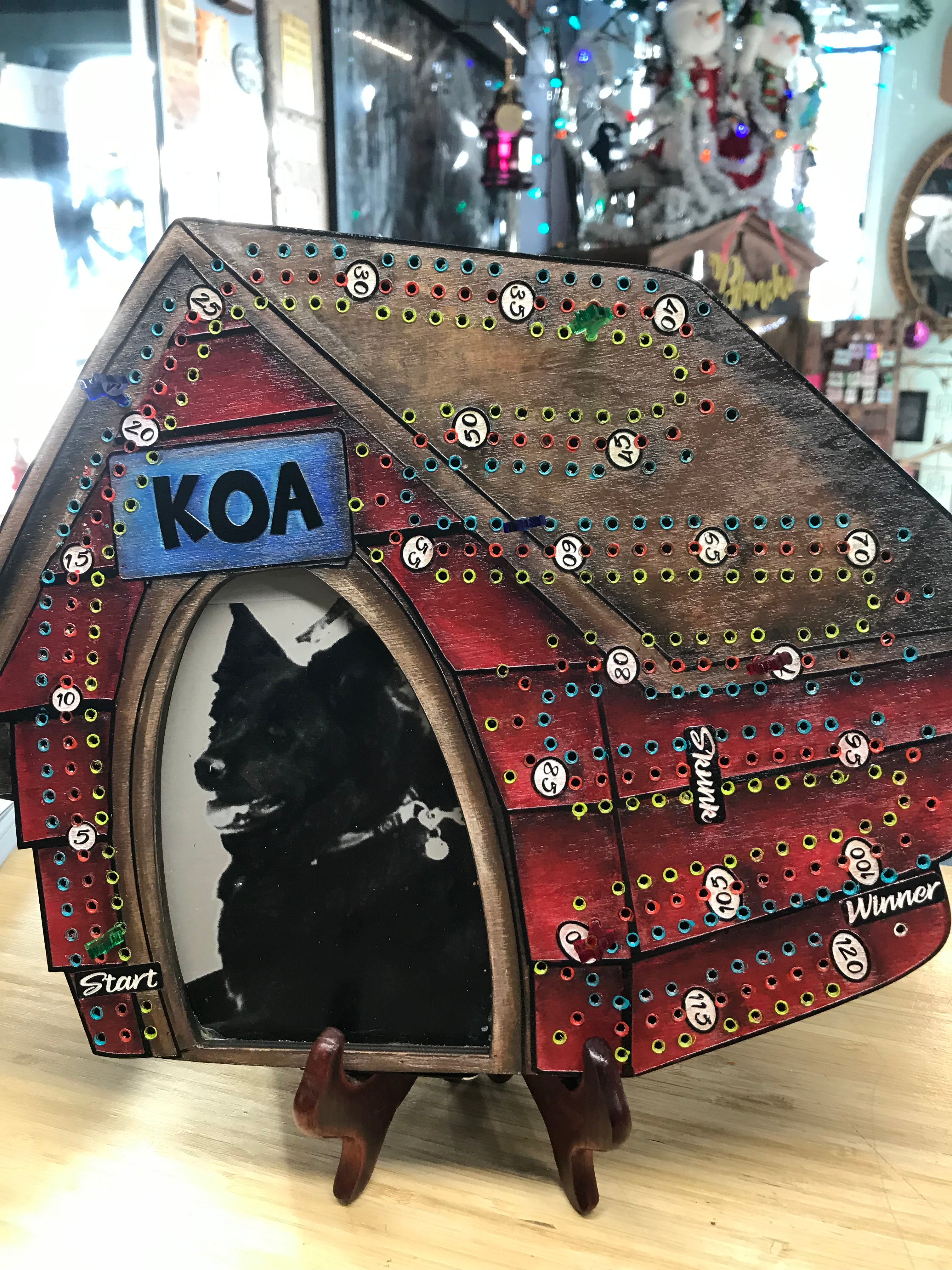 Decorative dog and dog house cribbage board with colorful pegs.