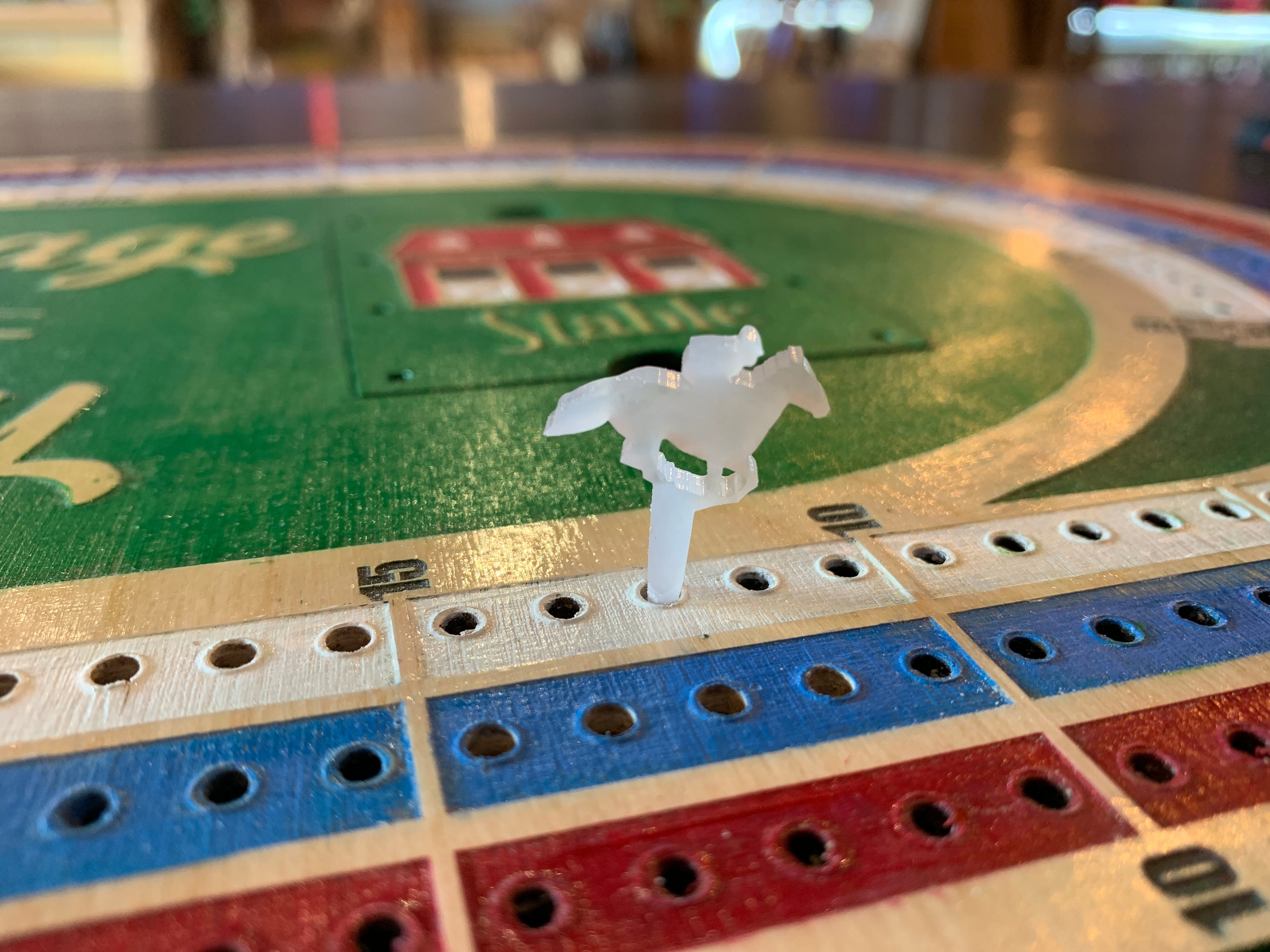 Close-up of a horse racing crib board game with a white horse figure acrylic peg.