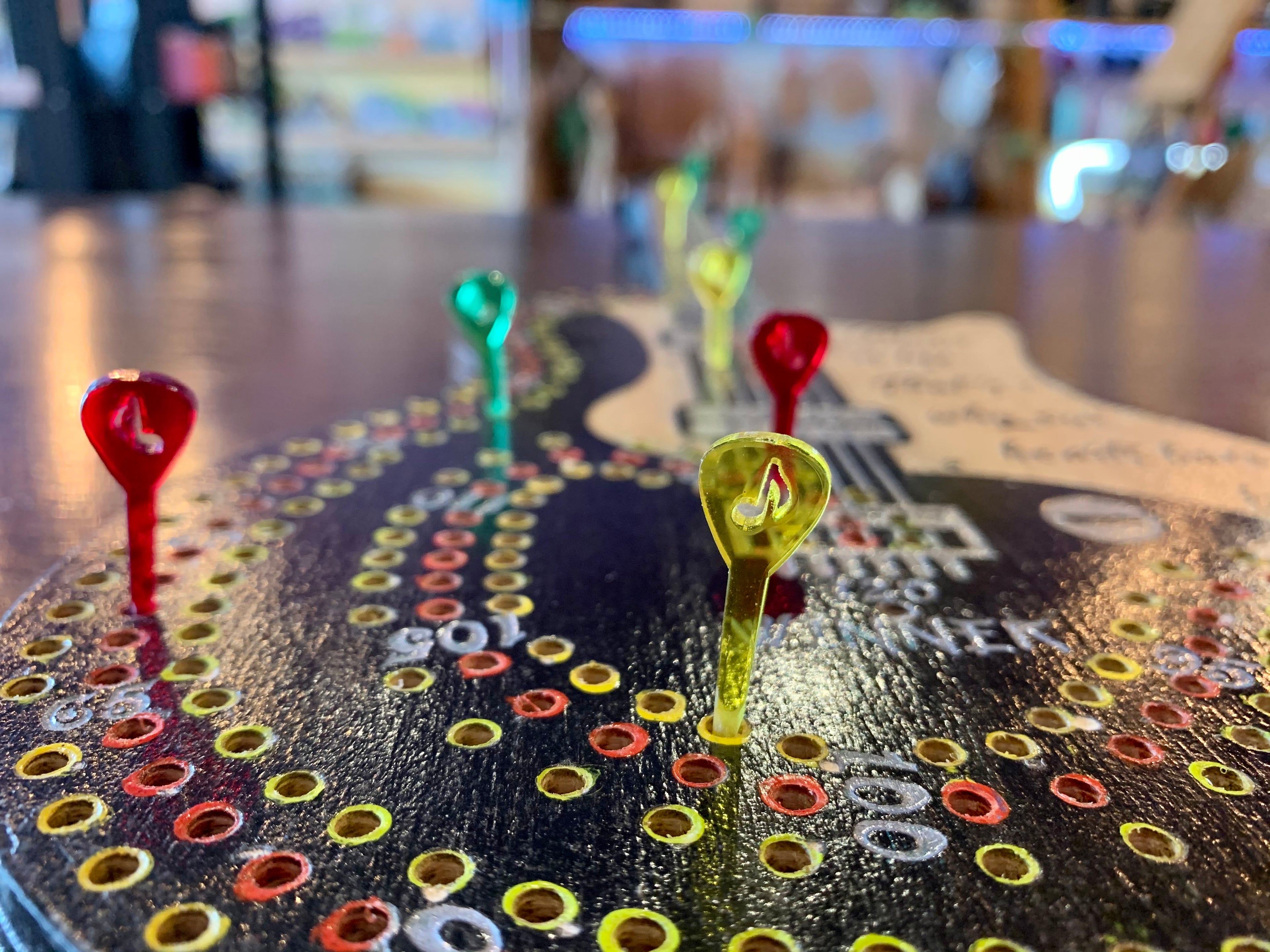 Decorative guitar cribbage board hand painted on a wooden surface with custom cut acrylic pegs