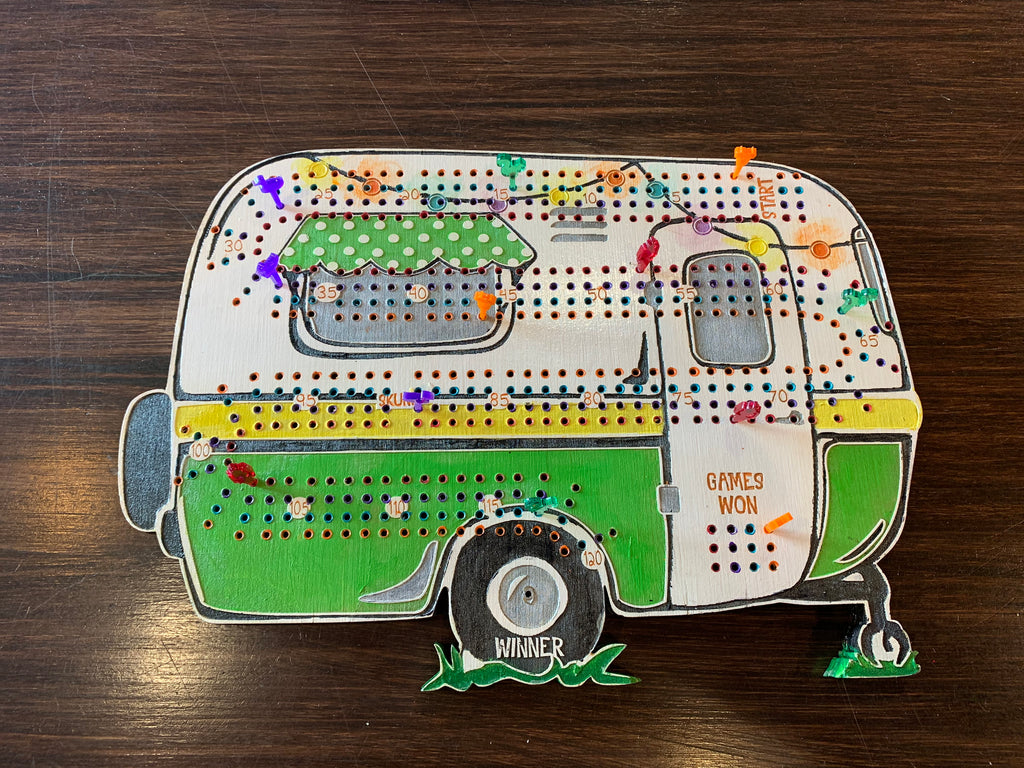 Decorative camper-shaped cribbage board on a wooden surface