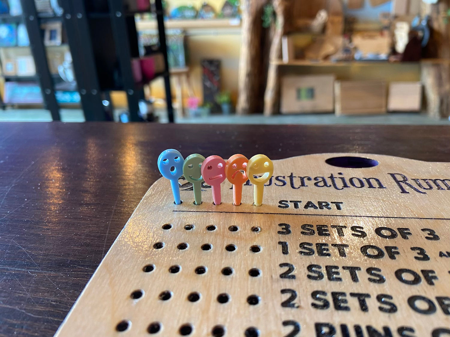 Colorful pegs on a wooden Frustration Rummy board.