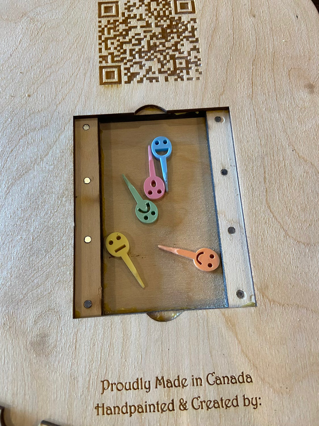 Frustration Rummy pegs with smiley faces on a wooden background with a QR code.