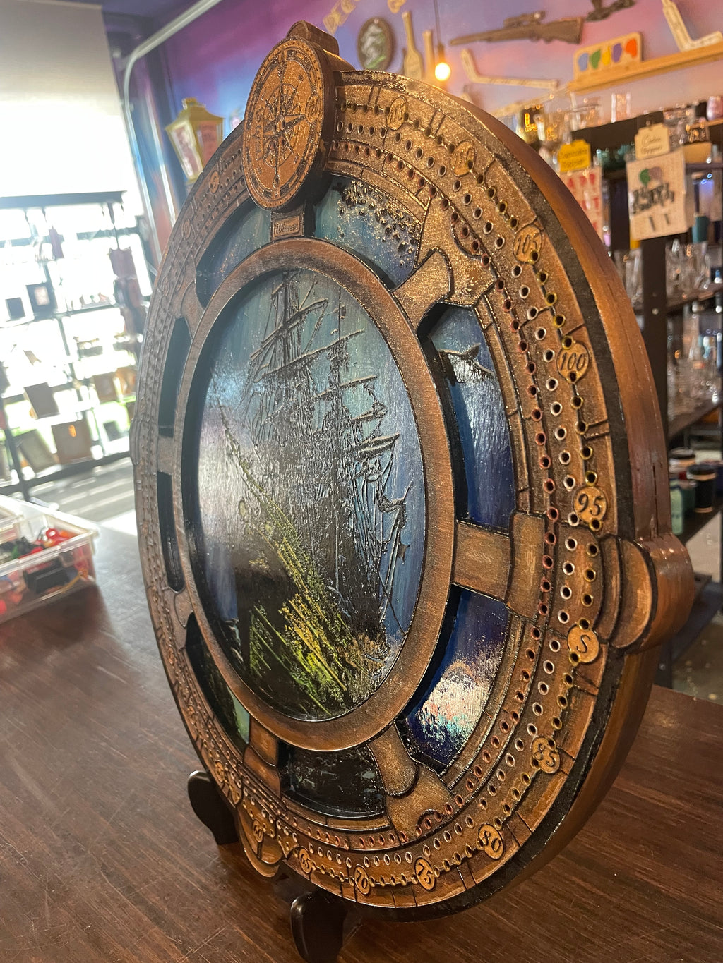 Decorative compass and ship wheel cribbage board with sunken ship.