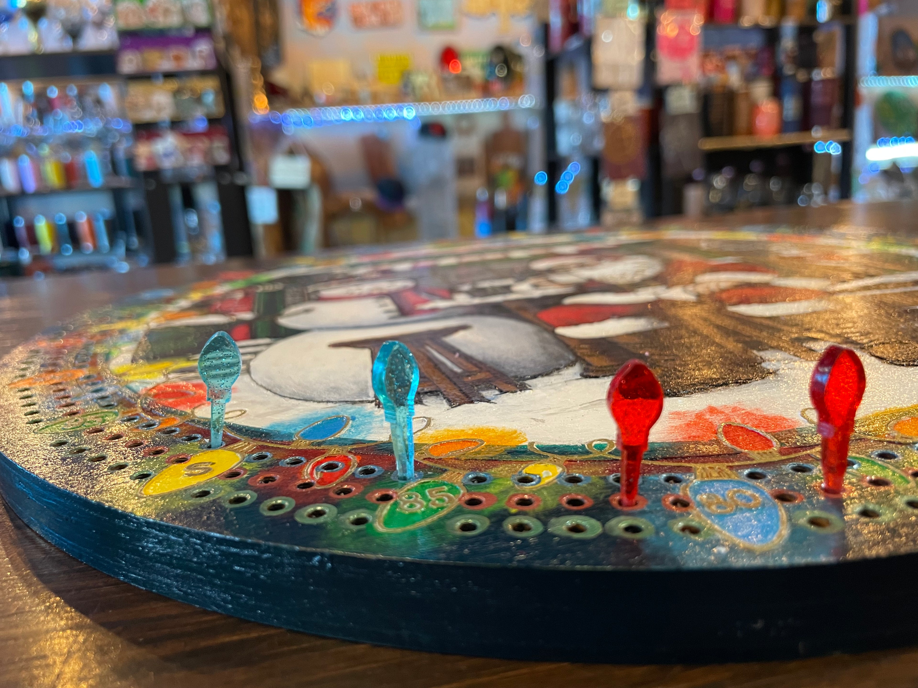 Close-up of a colorful board game with pegs on a wooden surface.