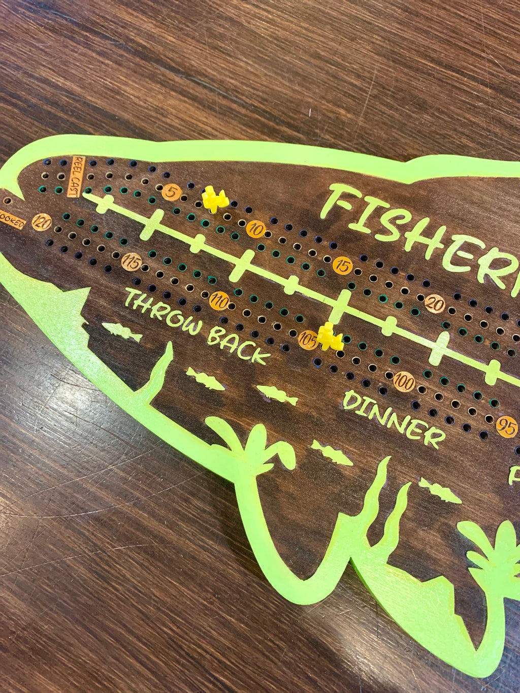 Wooden crib board with fishing-themed design.