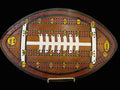 Wooden cribbage board shaped like a football.