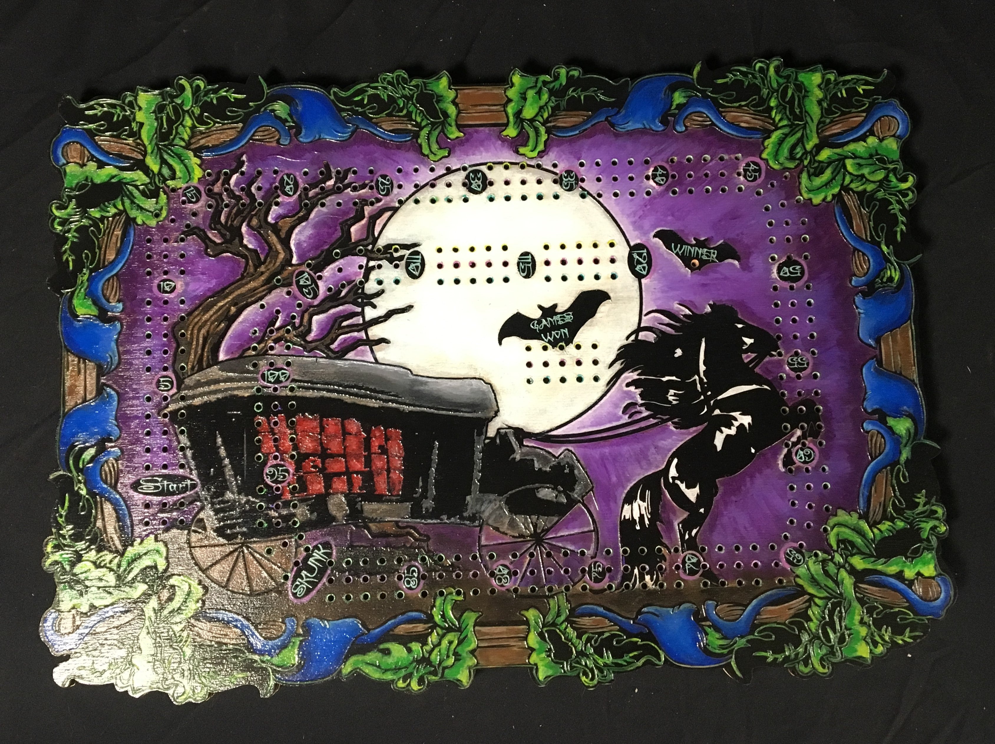 Halloween-themed cribbage board with a carriage, moon, and bats on a purple background.
