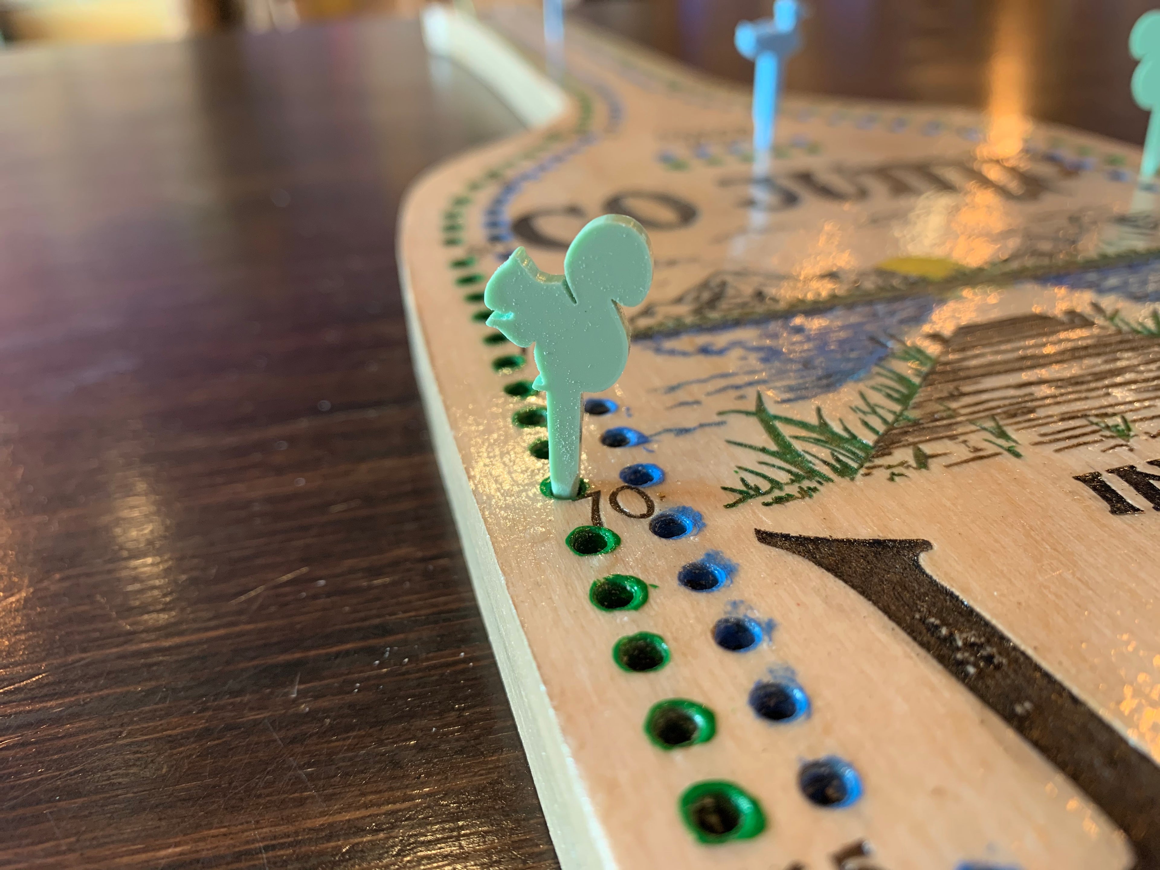Close-up of a cribbage board game with acrylic pegs.