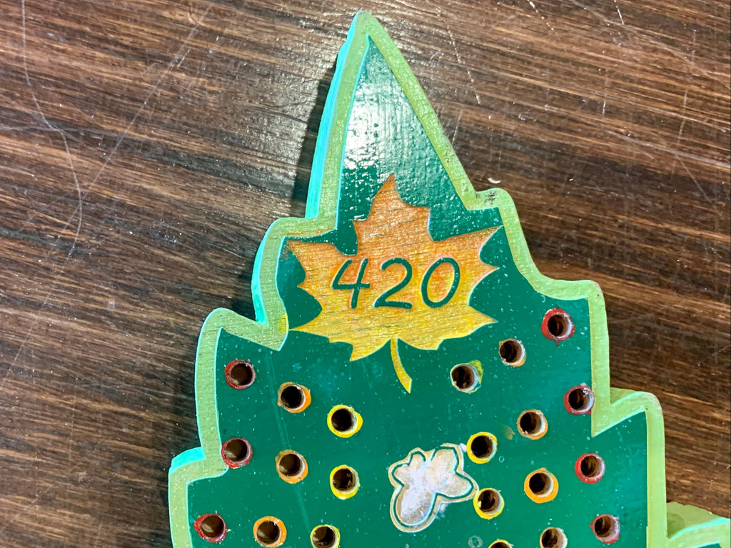 Close-up of a green wooden cribbage board with holes and 420.