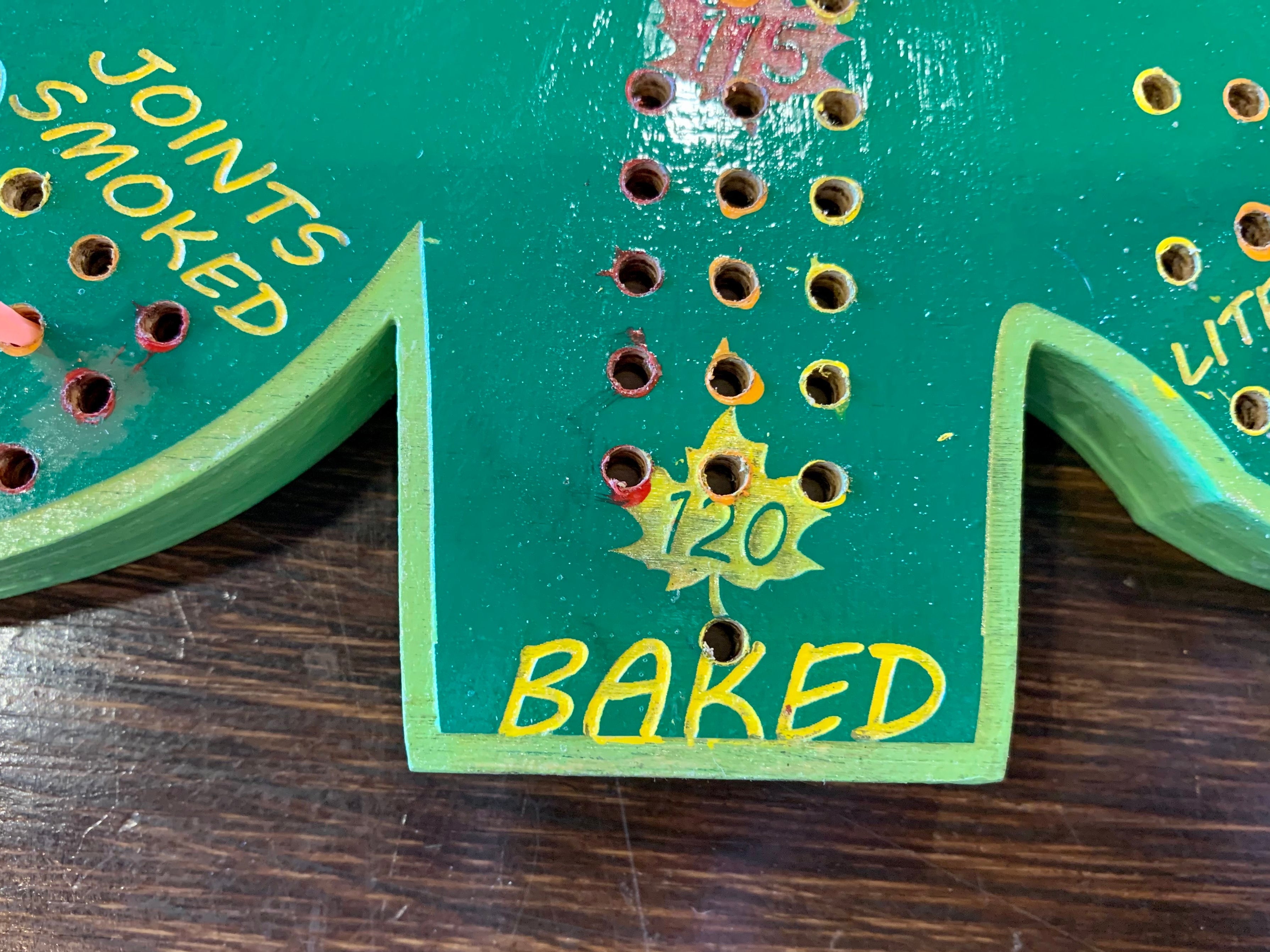Close-up of a green wooden cribbage board with holes.